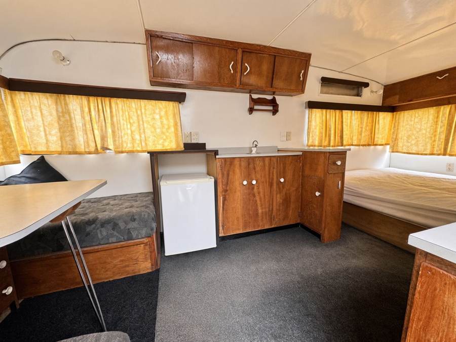 Caravan interior with double bed, kitchenette and dinette